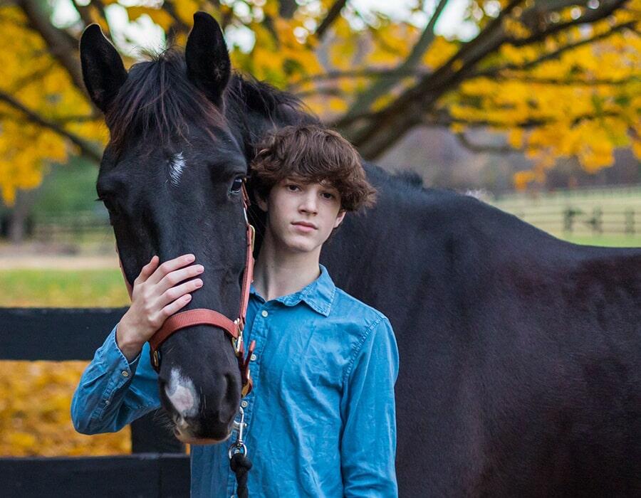 young man standing next to horse